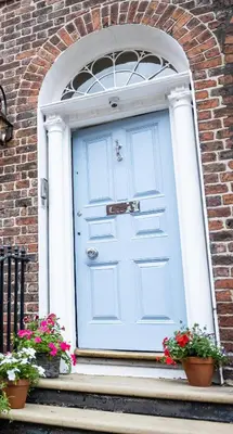 a white door on a brick building with flowers at Cosy Georgian Quarter Apartment - Sleeps 4 in Liverpool