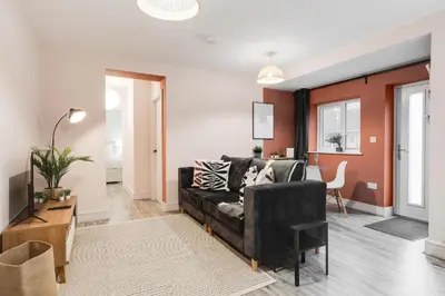 a living room with a black couch and red walls at Beach Stays - Ground Floor 2 Bed Apartment - Free Parking in Cleveleys