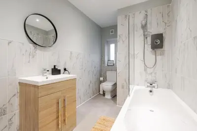 a bathroom with a tub and a sink and a mirror at Beach Stays - Ground Floor 2 Bed Apartment - Free Parking in Cleveleys