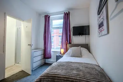 a bedroom with a bed and a window with purple curtains at Blackpool Retreat Group Stays in Blackpool