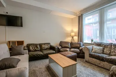 a living room with leather furniture and a flat screen tv at Blackpool Retreat Group Stays in Blackpool