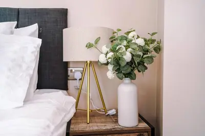 a vase of flowers on a table next to a bed at Cozy 2BR Flat in the Heart of Wigan Wallgate in Wigan