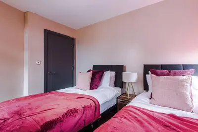 two beds sitting next to each other in a bedroom at Cozy 2BR Flat in the Heart of Wigan Wallgate in Wigan