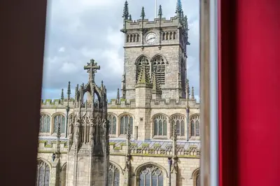 a large building with a clock tower with a cross at Cozy 2BR Flat in the Heart of Wigan Wallgate in Wigan