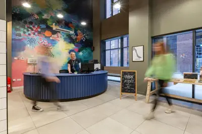 a woman standing at a counter in a room with people at For Students Only - True Liverpool in Liverpool