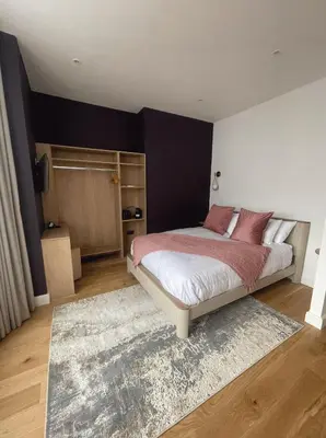 a bedroom with a bed with red pillows and a rug at Auberge in Lytham St Annes