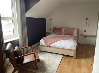 a bedroom with a bed with pink pillows and a chair at Auberge in Lytham St Annes