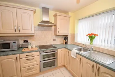 a kitchen with white cabinets and a sink and a microwave at Convenient 2 Bedroom Apartment in Preston w WiFi in Preston