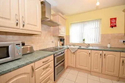 a kitchen with wooden cabinets and a microwave at Convenient 2 Bedroom Apartment in Preston w WiFi in Preston