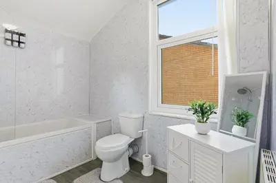 a white bathroom with a toilet and a window at The Crews Quarters Anfield - Sleeps 9 - Modern in Liverpool