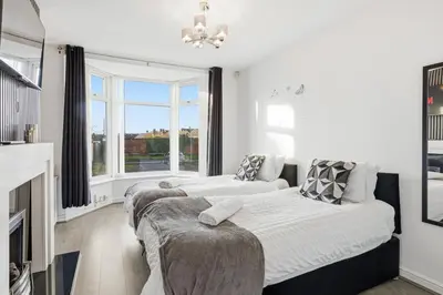 a white bedroom with two beds and a fireplace at The Crews Quarters Anfield - Sleeps 9 - Modern in Liverpool