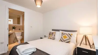 a white bedroom with a bed and a bathroom at Modern 2BR Near Liverpool ONE & Parking in Liverpool