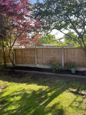 a wooden fence in front of a yard with trees at 1 Bed Apartment With Private Garden in Southport