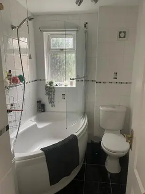 a bathroom with a tub and a toilet and a window at 1 Bed Apartment With Private Garden in Southport