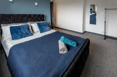 a large bed with blue pillows and a towel on it at Stylish 3 bedroom Wigan House sleeps 7 in Pemberton
