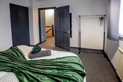 a bedroom with a bed with a green blanket on it at Stylish 3 bedroom Wigan House sleeps 7 in Pemberton
