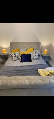 a large bed with yellow and blue pillows on it at Cambridge Villa St Annes in Lytham St Annes