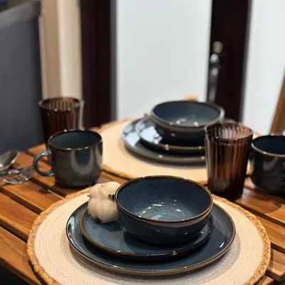 a wooden table with four black plates and cups at Cosy Parbold Apartment Steps form train station in Parbold