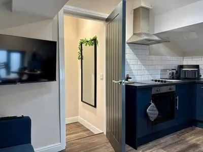 a kitchen with blue cabinets and a blue door at Cosy Parbold Apartment Steps form train station in Parbold
