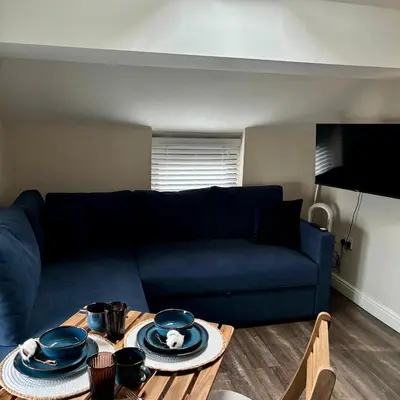 a living room with a blue couch and a table at Cosy Parbold Apartment Steps form train station in Parbold