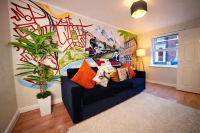a living room with a black couch and a mural at Preston Central in Preston