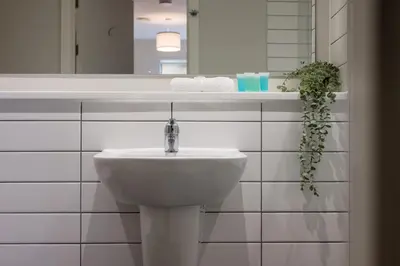 a white bathroom with a sink and a mirror at Modern 2BR 2BA Apartment in Liverpool - Sleeps 4 in Liverpool