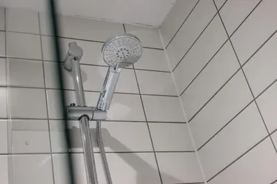 a shower head in a bathroom with white tiles at Modern 2BR 2BA Apartment in Liverpool - Sleeps 4 in Liverpool