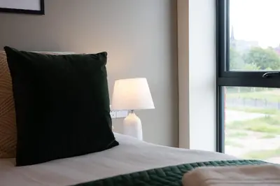 a bed with a pillow and a lamp next to a window at Modern 2BR 2BA Apartment in Liverpool - Sleeps 4 in Liverpool