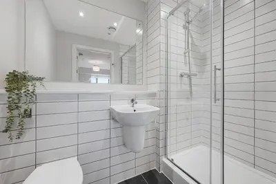 a white bathroom with a sink and a shower at Modern 2BR 2BA Apartment in Liverpool - Sleeps 4 in Liverpool