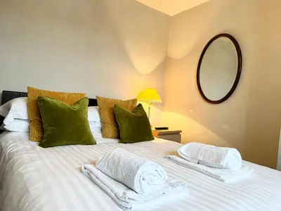 a bedroom with a large white bed with green pillows at Ulverston Cozy Cottage Retreat in Ulverston