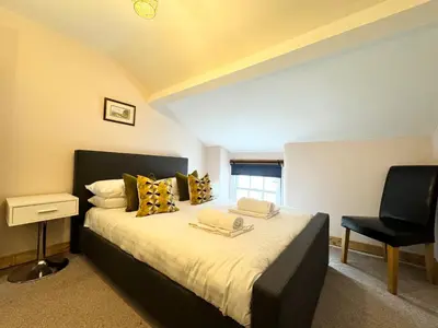 a bedroom with a large bed and a chair at Ulverston Cozy Cottage Retreat in Ulverston