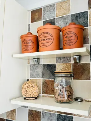a kitchen pantry with jars and nuts on shelves at Ulverston Cozy Cottage Retreat in Ulverston