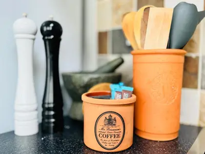 a cup of coffee sitting on a counter with utensils at Ulverston Cozy Cottage Retreat in Ulverston