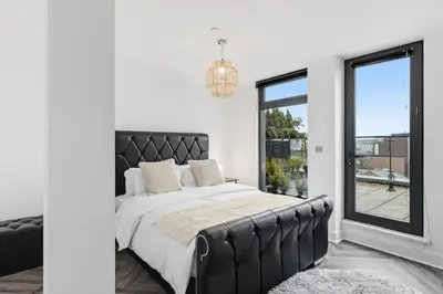 a bedroom with a black bed and a window at Skyline Penthouse- Views, Games 2 Parking Spaces in Liverpool