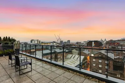 a balcony with a view of the city at sunset at Skyline Penthouse- Views, Games 2 Parking Spaces in Liverpool