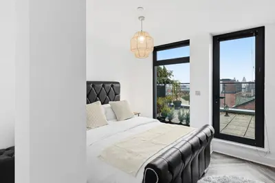 a bedroom with a bed and a large window at Skyline Penthouse- Views, Games 2 Parking Spaces in Liverpool
