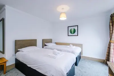 two beds in a room with white sheets at Slyne Lodge in Hest Bank