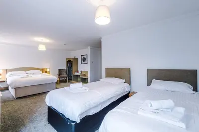 a hotel room with two beds and a desk at Slyne Lodge in Hest Bank