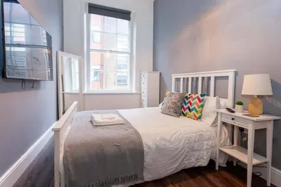a bedroom with a bed and a table with a lamp at Spacious 2BR -Liverpool Central - Walk to Royal Dock, Nightlife Train Station in Liverpool
