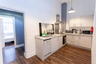 a kitchen with white cabinets and a wooden floor at Spacious 2BR -Liverpool Central - Walk to Royal Dock, Nightlife Train Station in Liverpool