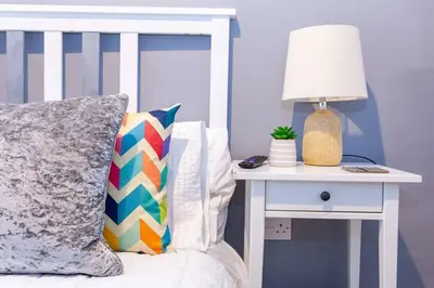 a bed with a lamp on a nightstand next to a side table at Spacious 2BR -Liverpool Central - Walk to Royal Dock, Nightlife Train Station in Liverpool