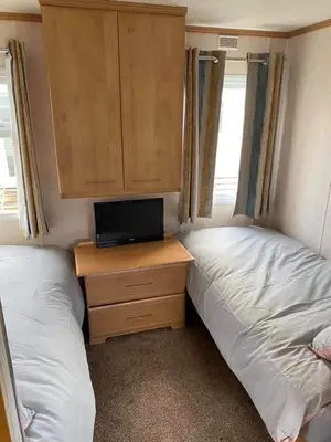a bedroom with two beds and a desk with a tv at Spacious Caravan Morecambe Parkdean caravan Park in Morecambe