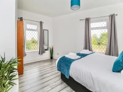 a bedroom with a large bed and two windows at 2 Bed House, Sleeps 5, Ideal for Contractors, St Helens, Long Term Stays Weekly & Monthly Offers in Saint Helens