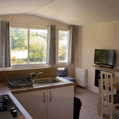 a kitchen with a sink and two windows and a television at Bowland Lakes Leisure Village in Forton