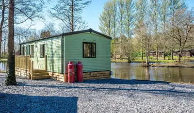 a green house with two red fire hydrants next to a river at Bowland Lakes Leisure Village in Forton