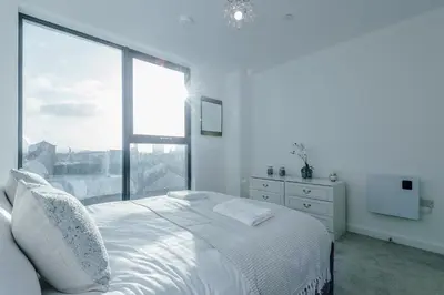 a white bedroom with a bed and a large window at Luxurious 2Bed Apartment, Sleeps 6, 3 beds in Preston
