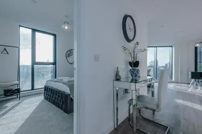 a bedroom with a bed and a table and a clock at Luxurious 2Bed Apartment, Sleeps 6, 3 beds in Preston