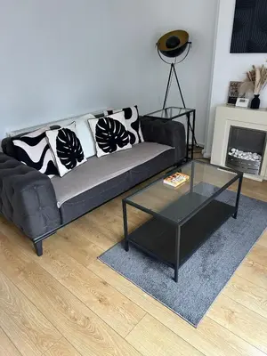 a living room with a black couch and a glass table at Merseyside cosy 2 bed townhouse sleeps 5 in Liverpool