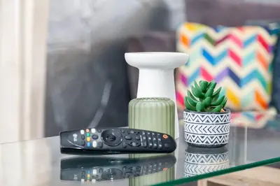 a remote control sitting on a glass table next to a vase at Close to City Centre - Mins Away from Anfield Stadium - Free Street Parking in Liverpool