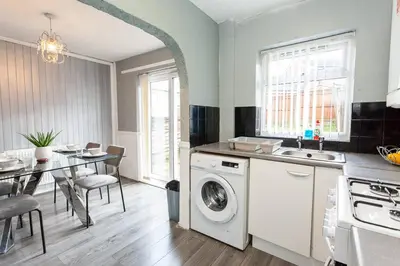 a kitchen with a washing machine next to a table at Close to City Centre - Mins Away from Anfield Stadium - Free Street Parking in Liverpool